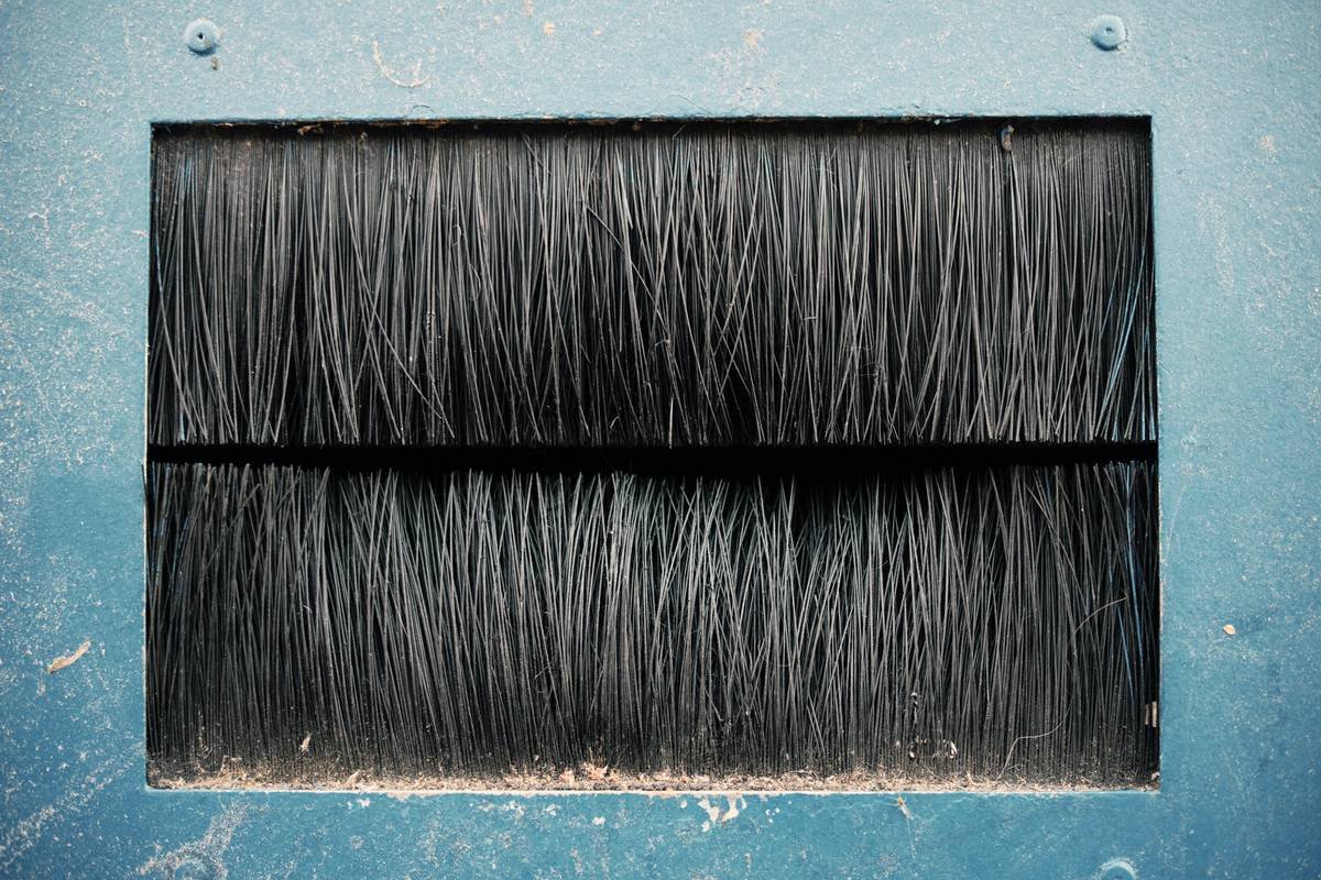 Diagram showing how negative ions from an ionic styling brush neutralize static charge on hair strands, smoothing the cuticle and reducing frizz