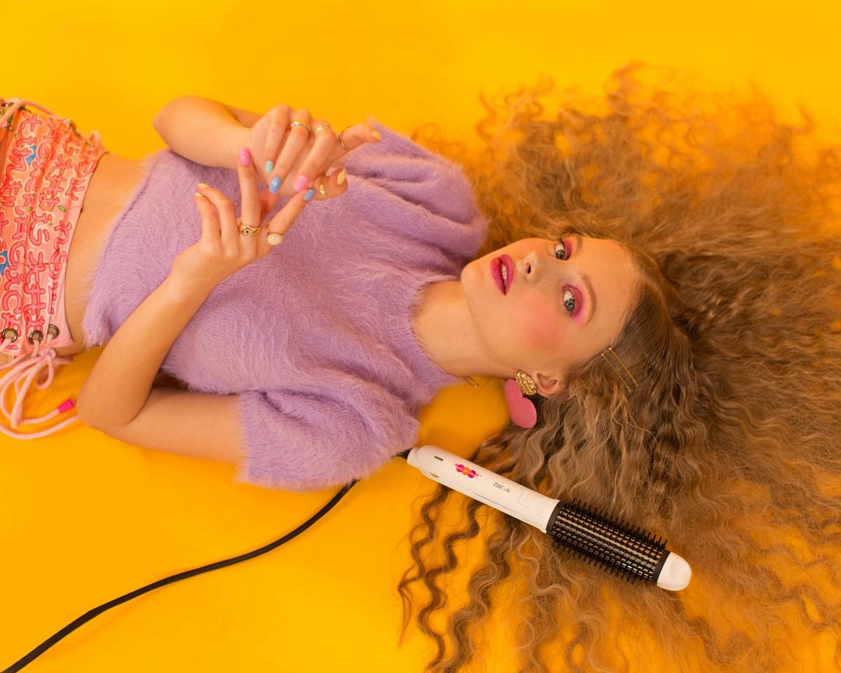 Woman using a hair curling brush on dry, sectioned hair with proper tension