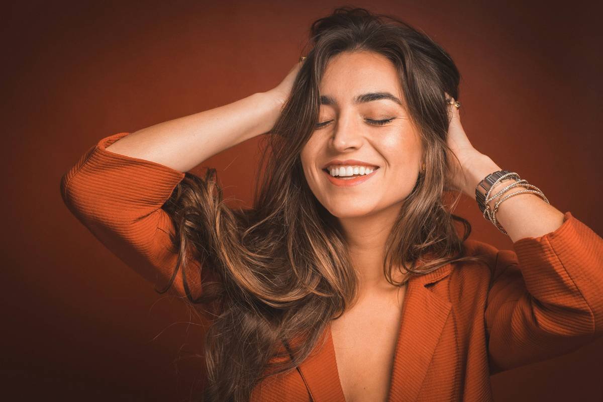woman gently brushing long hair with a wooden paddle brush labeled hair health product